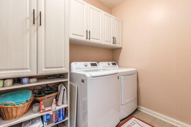 washroom featuring cabinet space, baseboards, washing machine and dryer, and light tile patterned floors