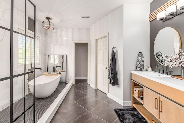 bathroom with visible vents, a walk in shower, vanity, an inviting chandelier, and a soaking tub