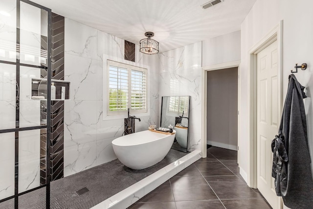 full bathroom with a freestanding bath, an inviting chandelier, walk in shower, and visible vents