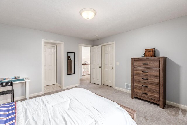 bedroom featuring baseboards, visible vents, and light colored carpet