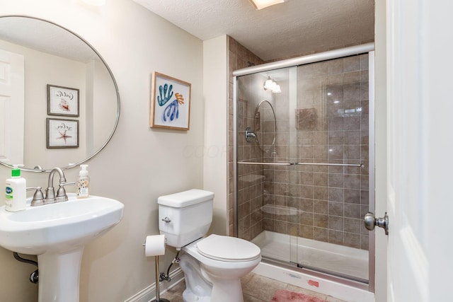 full bath featuring a textured ceiling, a stall shower, baseboards, tile patterned floors, and toilet