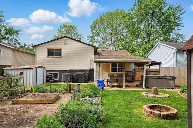 2680 Mellowbrook St, Columbus, OH 43232 - back of house with a hot tub, a vegetable garden, an outdoor fire pit, a patio, and a storage shed