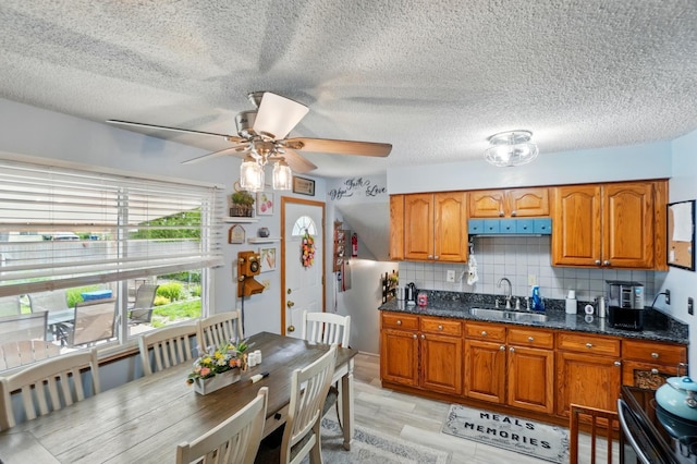 2680 Mellowbrook St, Columbus, OH 43232 - kitchen featuring a sink, brown cabinetry, a ceiling fan, decorative backsplash, and a textured ceiling