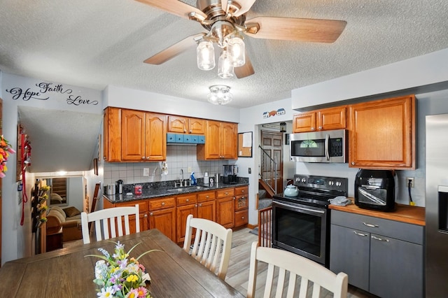 2680 Mellowbrook St, Columbus, OH 43232 - kitchen featuring appliances with stainless steel finishes, a textured ceiling, a ceiling fan, brown cabinets, and tasteful backsplash
