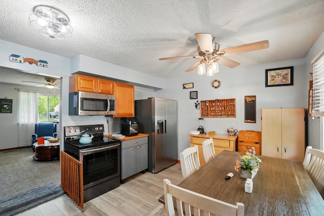 2680 Mellowbrook St, Columbus, OH 43232 - kitchen featuring stainless steel appliances, ceiling fan, a textured ceiling, light wood finished floors, and brown cabinets
