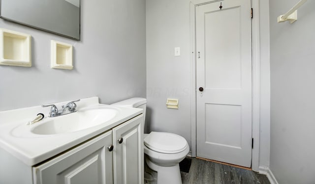 bathroom with wood finished floors, toilet, and vanity