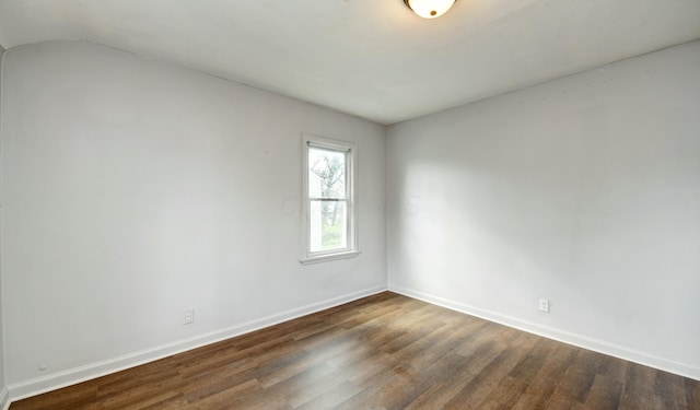spare room featuring baseboards, lofted ceiling, and wood finished floors