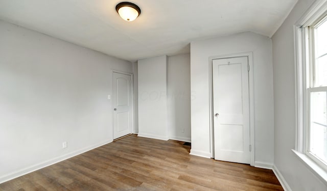 unfurnished bedroom with baseboards, wood finished floors, and multiple windows