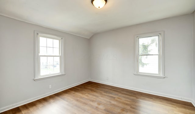 spare room with lofted ceiling, plenty of natural light, baseboards, and wood finished floors