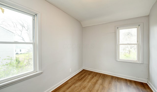 unfurnished room featuring baseboards, vaulted ceiling, and wood finished floors