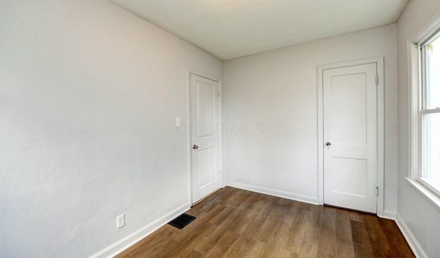 empty room featuring baseboards, visible vents, and dark wood-style flooring
