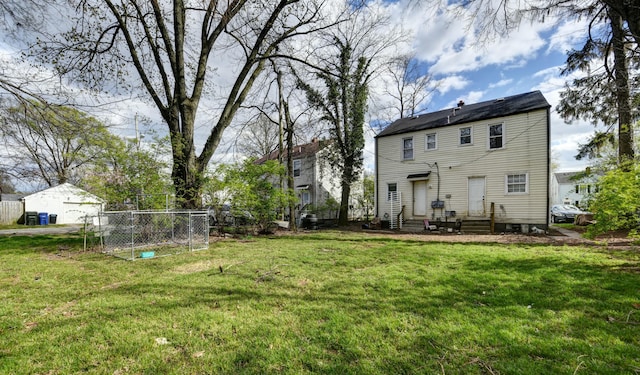 back of property with a lawn, fence, and entry steps