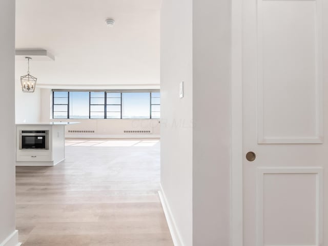 1620 E Broad St Unit 1106, Columbus, OH 43203 - hallway with light wood-style flooring, a chandelier, and baseboards