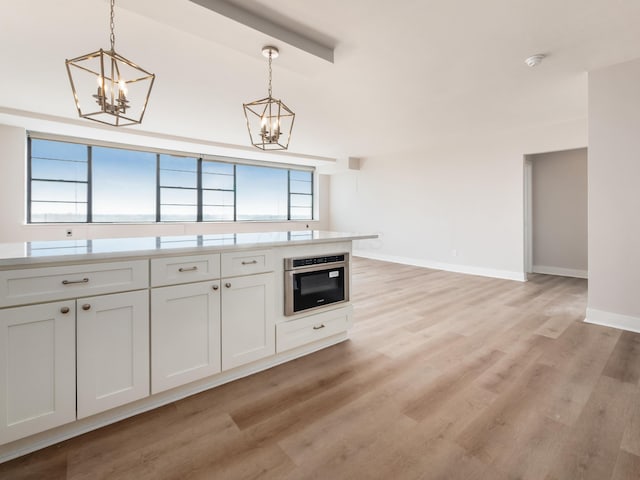 1620 E Broad St Unit 1106, Columbus, OH 43203 - kitchen featuring a chandelier, stainless steel oven, pendant lighting, and light wood finished floors