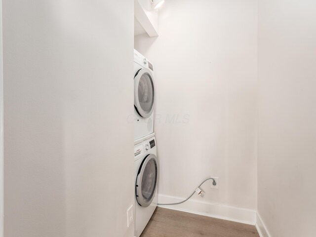 1620 E Broad St Unit 1106, Columbus, OH 43203 - clothes washing area featuring stacked washer and clothes dryer, light wood-style floors, and baseboards