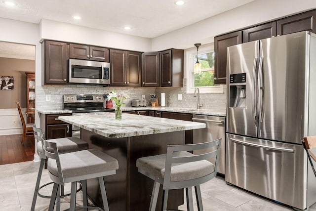 1123 Firth Ave, Worthington, OH 43085 - kitchen featuring stainless steel appliances, dark brown cabinets, a sink, a kitchen bar, and tasteful backsplash