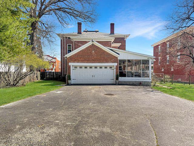 59 S Chillicothe St, South Charleston, OH 45368 - view of front of property featuring a chimney, fence, driveway, brick siding, and a sunroom