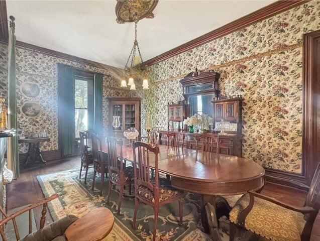 59 S Chillicothe St, South Charleston, OH 45368 - dining area featuring baseboards, a chandelier, wallpapered walls, wood finished floors, and ornamental molding