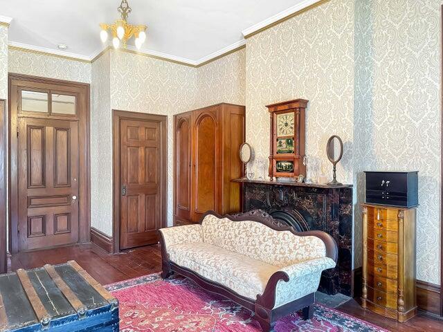 59 S Chillicothe St, South Charleston, OH 45368 - living area with crown molding, wallpapered walls, hardwood / wood-style flooring, an inviting chandelier, and baseboards