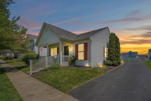 bungalow featuring covered porch, driveway, and a shingled roof