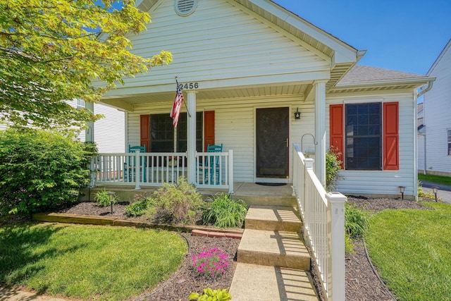 bungalow with covered porch, roof with shingles, and a front yard