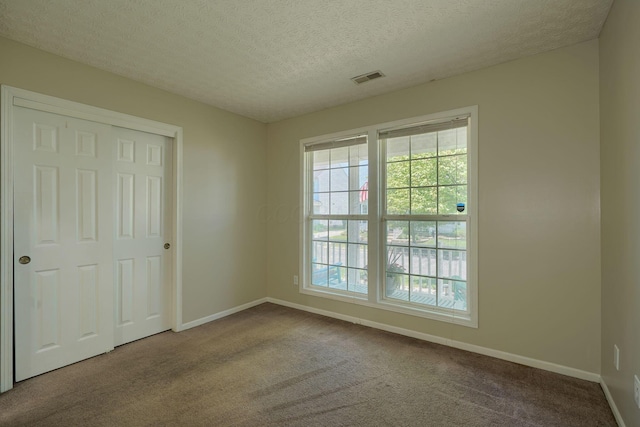 empty room featuring carpet flooring, baseboards, and a textured ceiling