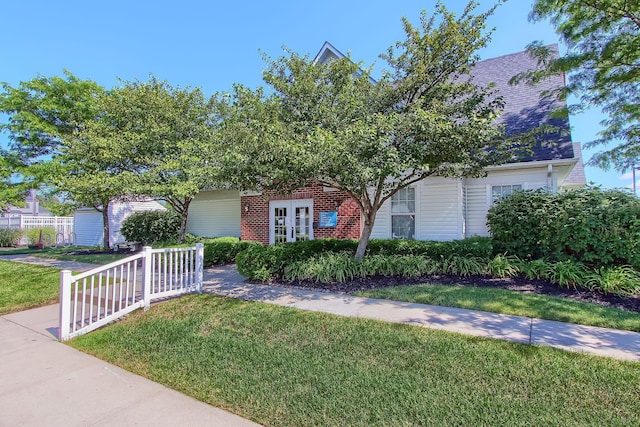 view of property hidden behind natural elements with brick siding and a front lawn