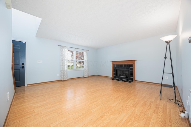 1418 Brookforest Dr, Columbus, OH 43204 - unfurnished living room with a tiled fireplace, light wood-style flooring, and baseboards