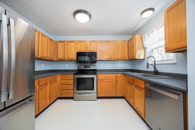 1418 Brookforest Dr, Columbus, OH 43204 - kitchen with dark countertops, a textured ceiling, appliances with stainless steel finishes, and a sink