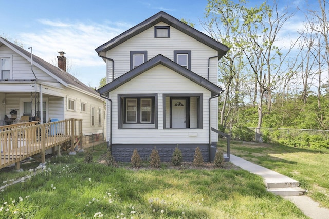 view of front of property with a front yard, a deck, and fence