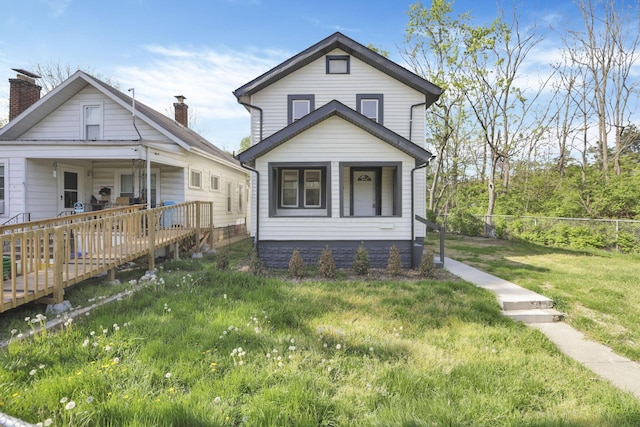 view of front of house with a front yard, a wooden deck, a chimney, and fence