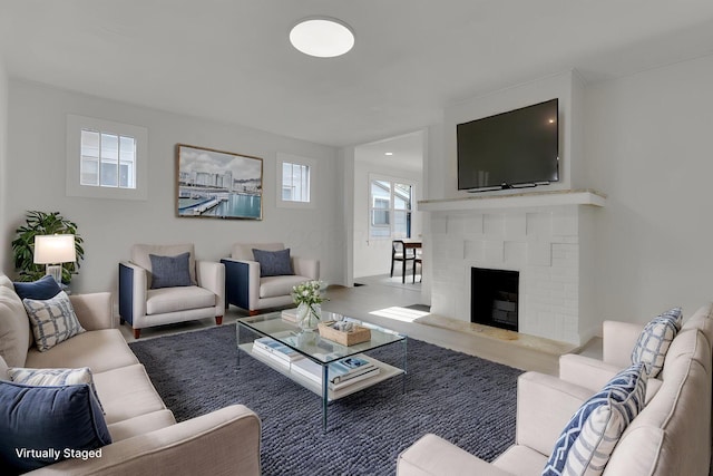 living room with a brick fireplace and wood finished floors