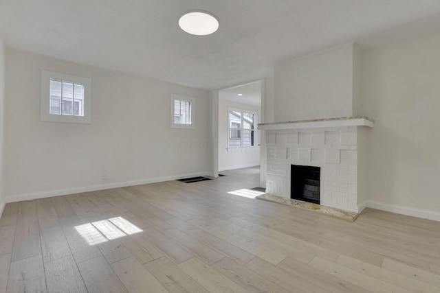 unfurnished living room featuring a brick fireplace, visible vents, wood finished floors, and baseboards