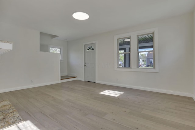 unfurnished living room featuring baseboards and light wood finished floors