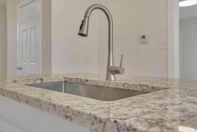 room details featuring a sink and light stone counters