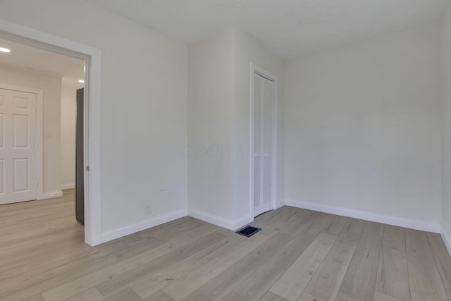 spare room with baseboards and light wood-style floors