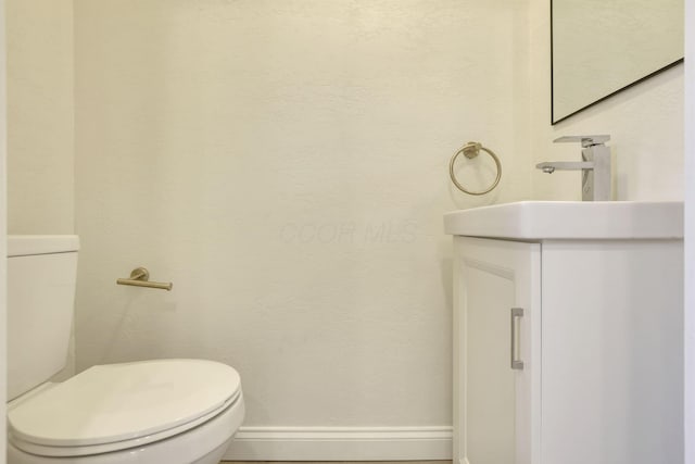 bathroom featuring vanity, toilet, and baseboards