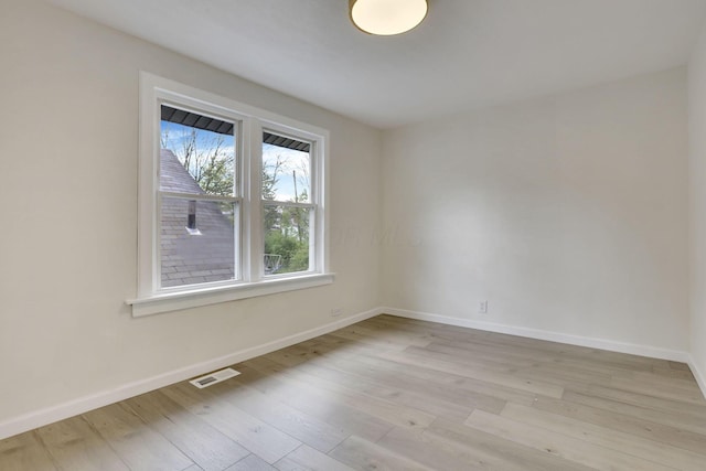 spare room featuring baseboards, visible vents, and light wood-style flooring