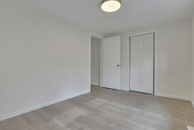 unfurnished bedroom with light wood-style floors, baseboards, and a closet