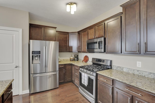 3884 Winding Oaks Dr, Columbus, OH 43228 - kitchen with dark brown cabinets, light stone countertops, dark wood-style floors, a textured ceiling, and appliances with stainless steel finishes