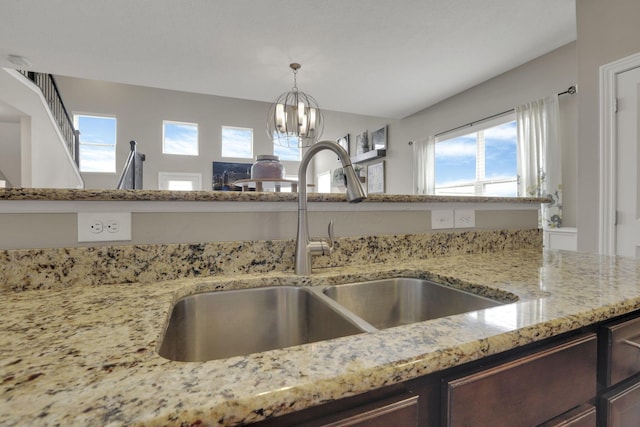 3884 Winding Oaks Dr, Columbus, OH 43228 - interior details featuring hanging light fixtures, dark brown cabinets, a sink, light stone counters, and a chandelier