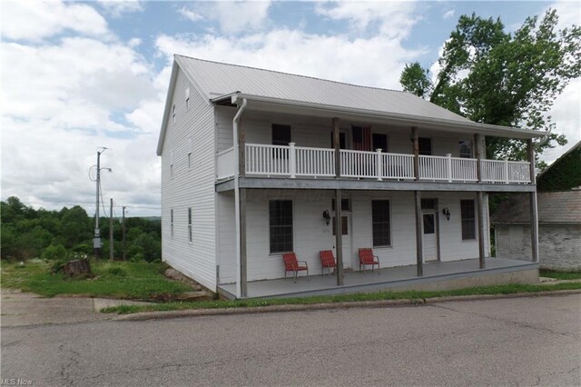 view of front facade with metal roof, a porch, and a balcony