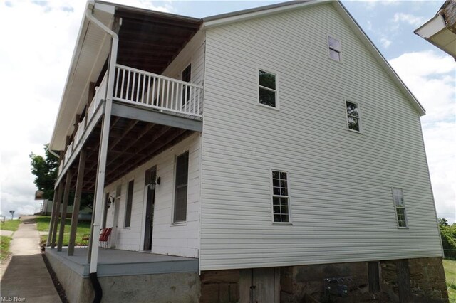 view of property exterior with covered porch and a balcony