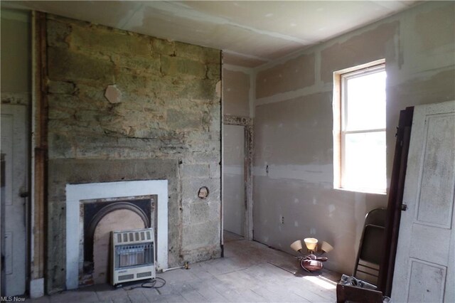 unfurnished living room featuring heating unit and a wood stove
