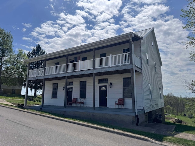 townhome / multi-family property featuring covered porch, a balcony, and metal roof