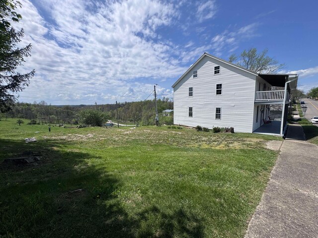 view of side of property featuring a patio, a yard, and a balcony