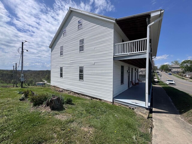 view of side of property with a patio area, a balcony, and a yard