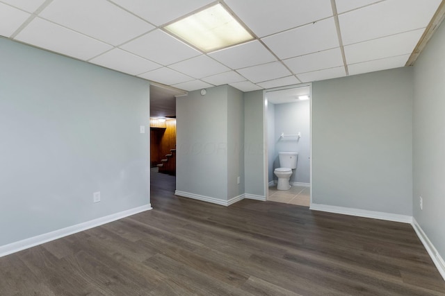 empty room featuring baseboards, a paneled ceiling, wood finished floors, and stairway