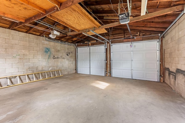 garage featuring concrete block wall and a garage door opener