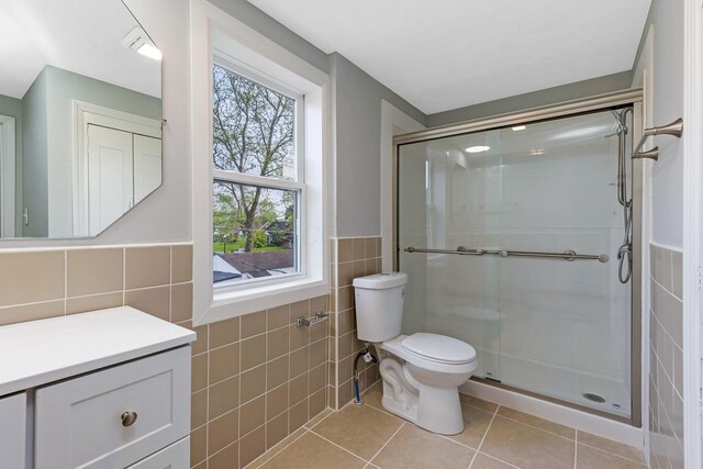 bathroom featuring tile walls, tile patterned flooring, a stall shower, and toilet